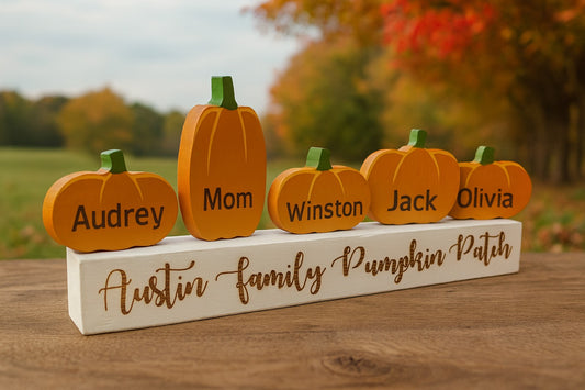 Wooden pumpkin family display with names on a wooden base outdoors.
